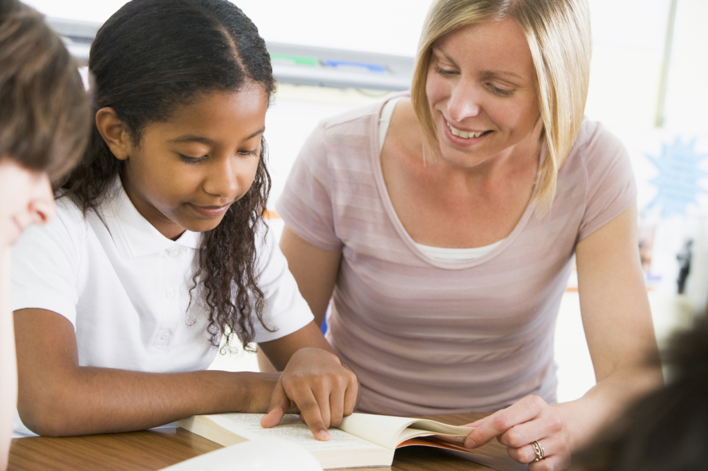 Image of a Schoolgirl and teacher reading a book in class