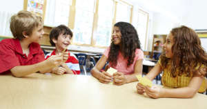 Image of Four young children playing cards in their classroom together