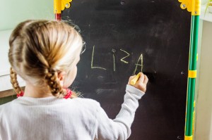 Child writing her name on chalk board