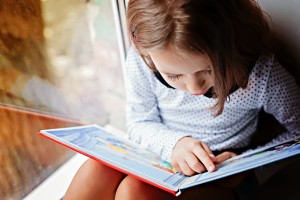 Young child pointing to words while reading