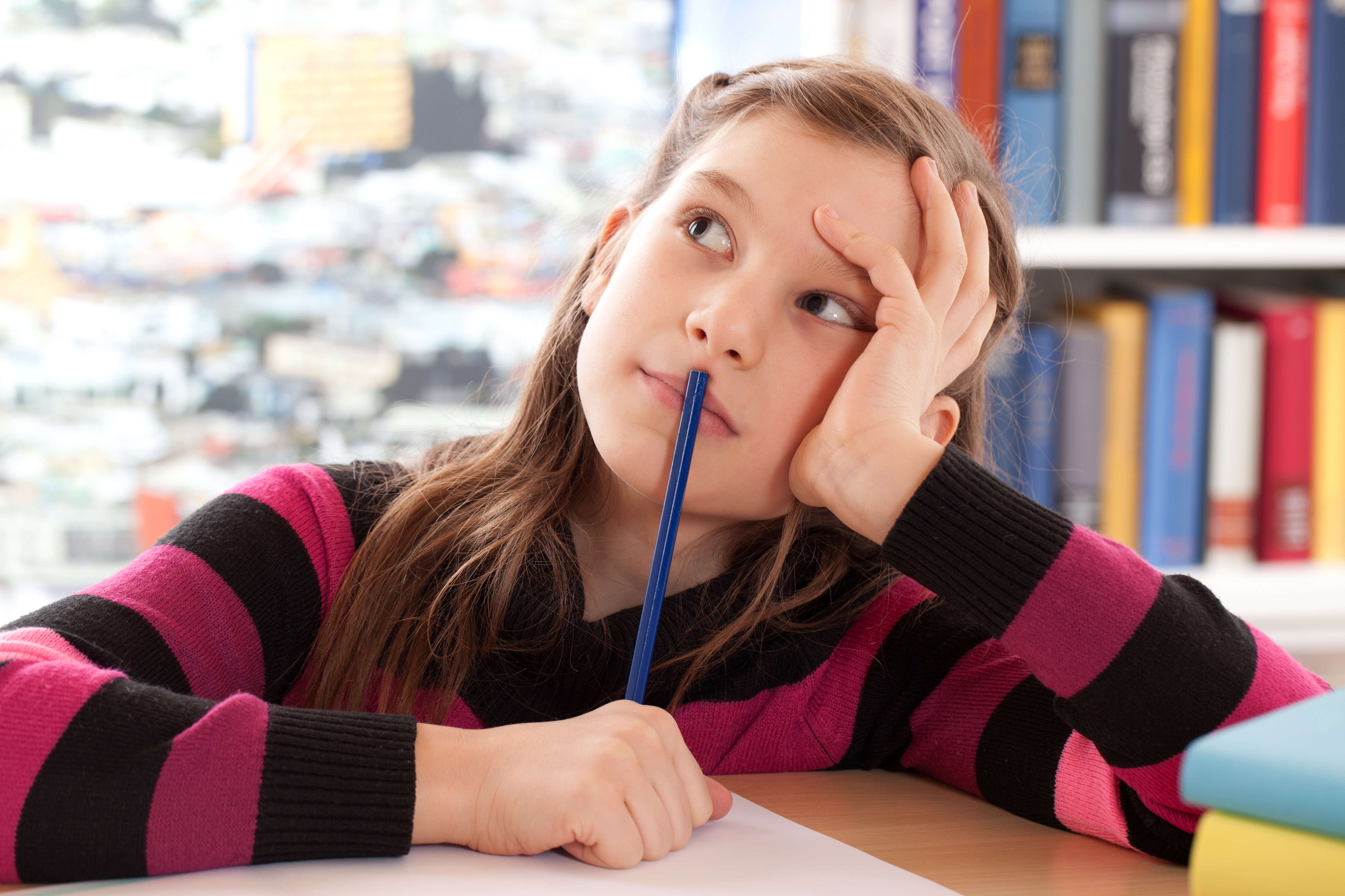 Young girl holding pencil, deep in thought
