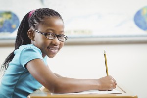 Smiling pupil working at her desk in a classroom