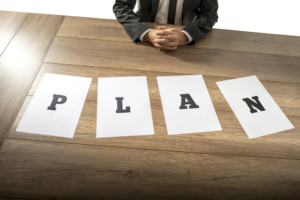 Man at a desk with papers that read "plan"