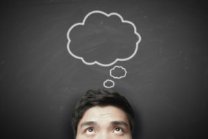 picture of a man with a thought bubble drawn on a chalk board behind him