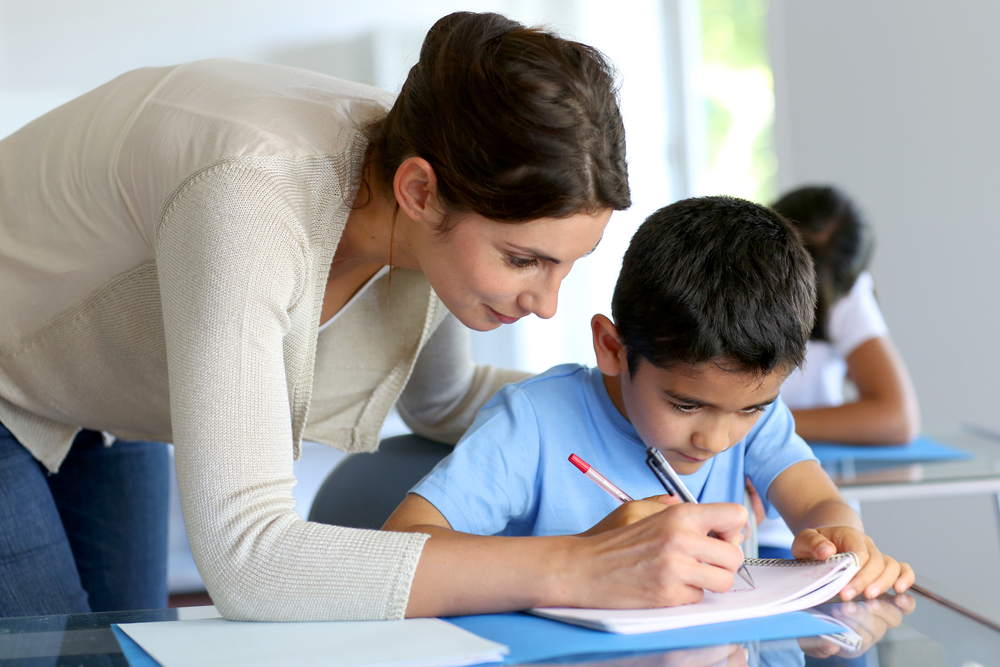 Teacher helping a student learn to write