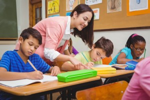Teacher helping a student sitting at a desk next to two other students