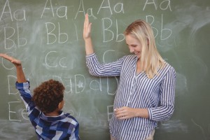 Teacher and student give a high-five with the alphabet on the blackboard
