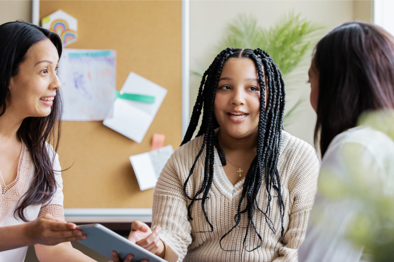 Student and caregiver meeting with an educator in a school setting