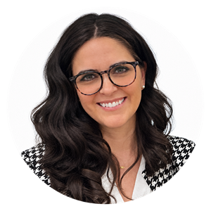 Circular headshot of Alex-Andrée Madore smiling at the camera, wearing glasses, a black-and-white patterned blazer, and a white blouse.