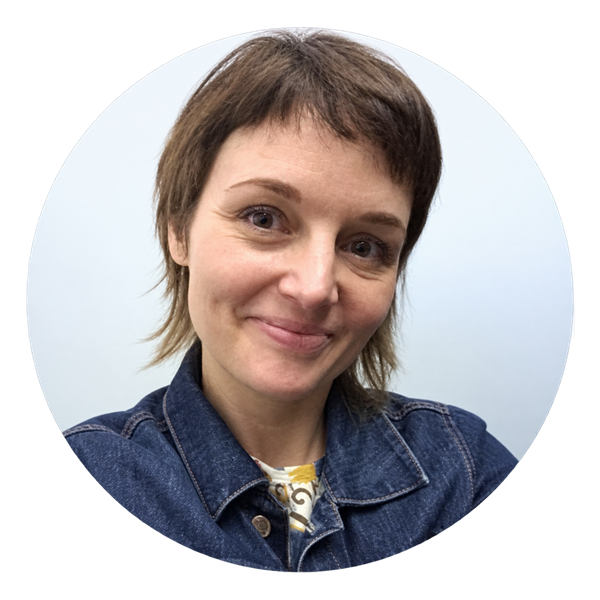 Portrait of Dr. Laurie Faith smiling at the camera, wearing a dark denim jacket against a light background.